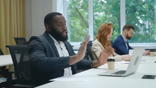 Африканский американский бизнесмен говорит на видео-конференции онлайн на ноутбуке в офисе. Работая в офисе, мужчина-работник получает видеозвонок на ноутбук. — стоковое видео