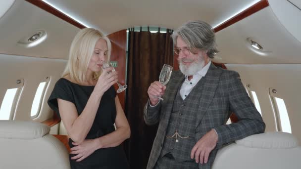 Πλούσιο ζευγάρι πολυτελείας που ταξιδεύει με ιδιωτικό τζετ. Senior άνδρας και γυναίκα απολαμβάνοντας vip ρομαντικό ταξίδι με ποτήρια σαμπάνιας, ενώ πετούν στην πρώτη θέση αεροπορικές εταιρείες — Αρχείο Βίντεο
