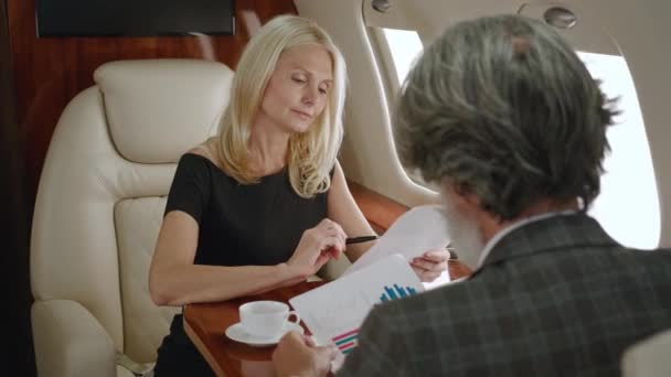 Couple riche homme d'affaires mature et femme d'affaires travaillant avec des graphiques, étudier la stratégie de croissance de l'entreprise lors d'un voyage d'affaires en jet privé ou avion de première classe — Video