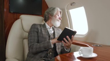 Klasik takım elbiseli, şık, olgun zengin bir adam özel uçakla uçarken kitap ya da not defteri okuyor. Uçak camından bakan kendine güvenen CEO iş adamı. Özel jetle seyahat eden lüks..