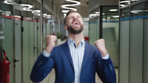 Возбужденный молодой бизнесмен в официальном костюме показывает жест "да". Счастливый победитель-мужчина, празднующий успех в бизнесе, удивленный перед камерой, стоящий в офисе. Идея победы. — стоковое видео