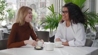 Açık havada kafede oturan iki çekici kadın, iletişim kurup komik hikayeler anlatırken, dışarıda rahatça vakit geçiriyorlar. Kafede oturup dedikodu yapan ve çay içen iki farklı bayan arkadaş.