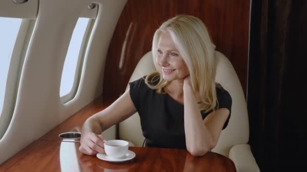 Belle femme d'affaires mature réussie voyage en avion privé. Portrait d'une femme âgée riche buvant du thé ou du café tout en profitant d'un voyage de luxe dans des compagnies aériennes de première classe affaires — Video