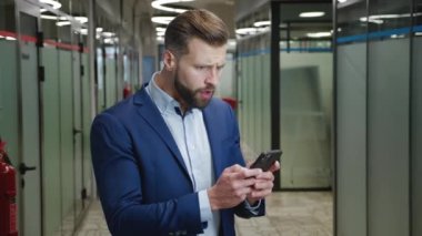 Stresli işadamı ofis koridorunda dururken akıllı telefon kullanırken şok oluyor. Ne yazık ki şaşırmış ve korkmuş bir iş adamı cep telefonundan kötü haberler okumaktan endişeleniyor..