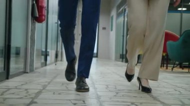 Koridorda yürüyen iş adamları. Ofis koridorunda yürüyen resmi takım elbiseli tanınmayan işadamı ve iş kadınının ön ayakları..