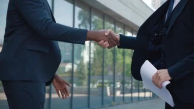 Resmi takım elbiseli iki Afrikalı ve Kafkasyalı iş merkezinde el sıkışıyorlar. Erkek iş adamları buluşuyor. Ortaklar toplantısı.