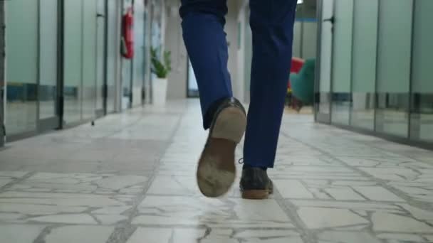 Rastreamento de pernas de homem de negócios em terno formal que anda ao longo do corredor de escritório. Traseira vista para trás pés de empreendedor masculino irreconhecível andando pelo corredor do escritório de espaço aberto. — Vídeo de Stock