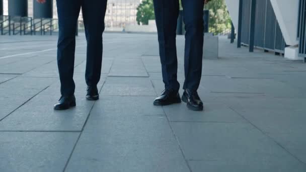 İşe gidip gelen iki iş adamının ön ayakları. Deri ayakkabılı ve resmi takım elbiseli kendine güvenen adamlar iş yerinin caddesi boyunca yürüyorlar. — Stok video