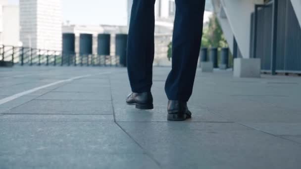 İşe gidip gelen bir iş adamının dikiz ayağında. Kendine güvenen deri ayakkabılı ve resmi takım elbiseli bir adam şehir merkezinde ofis binasının yanında yürüyor.. — Stok video