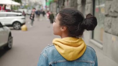 Şehir merkezinde kot ceketli, yürüyen bir şehirde şık bir Afro-Amerikan kadını. Arka planda, geçmişi bulanık, yoğun şehir hayatı olan genç bir kız öğrencinin karşıdan karşıya geçişi..