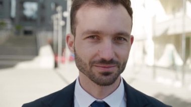 Kameraya bakan gülümseyen CEO 'nun portresi. 30 'lu yaşlarda erkek işadamı klasik takım elbise giyiyor ve modern ofis arka planında dışarıda poz veriyor.