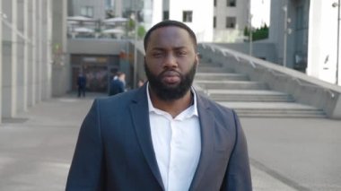 Klasik takım elbiseli özgüvenli Afrikalı iş adamının portresi modern ofis arka planında dışarıda poz veriyor.