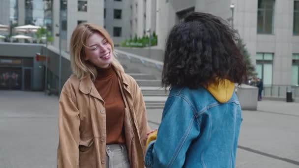 Дві молоді жінки зустрічаються і обіймаються на вулиці — стокове відео