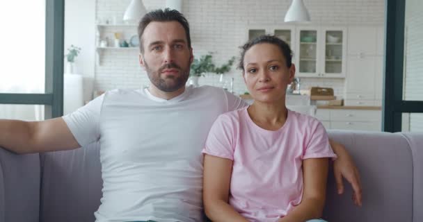 Vidéo 4K portrait en gros plan confiant de charmant couple d'âge moyen assis sur le canapé dans le salon. Mari et femme assis près l'un de l'autre sur le fond de la cuisine — Video