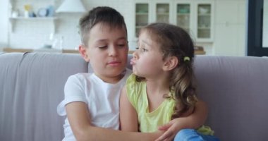 Şefkatli bir ağabey kız kardeşine şefkatle sarılır, onunla konuşur, oturma odasındaki kanepede oturur. Arkadaşlık, sevgi ve ilgiyle mutlu aile ilişkisinin 4K videosu