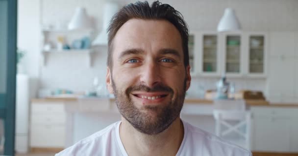 4K відео. Зведіть портрет вродливого дорослого бородатого європейця, який посміхається з зубатою посмішкою, дивлячись на камеру на кухні. Портрет вродливого кавказького чоловіка. — стокове відео