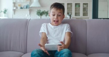 4K video portresi. Yakışıklı, heyecanlı okul çocuğu. Aktif olarak bilgisayar oyunlarında akıllı telefonla oynuyor ve kazanırken yumrukla hareket ediyor..