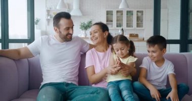 Anne ve baba en büyük oğlunun yanında otururken birbirlerine gülümserler ve herkes ellerini çırpan kıza doğru eğilir. Aşk, şefkat ve şefkat konsepti.