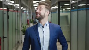 Şok olmuş takım elbiseli yakışıklı işadamının portresi. Genç bir erkek kameraya hoş bir şekilde şaşırır. Şok sevinci bir ilgi hisseder. Modern ofis geçmişiyle ilgili beklenmedik iyi haberler alır..