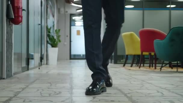Vista frontal pés de empreendedor masculino irreconhecível andando pelo corredor do escritório de espaço aberto. Rastreamento de pernas de homem de negócios em terno formal andando ao longo do corredor de escritório. — Vídeo de Stock