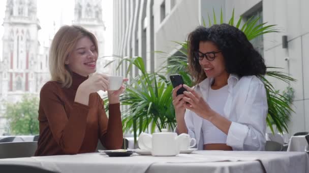 Attrayant jeunes femmes prenant des photos dans le café posant en regardant la caméra smartphone. — Video