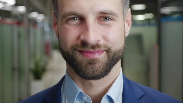 Primo piano di un uomo d'affari sorridente con la barba che guarda alla telecamera. Ritratto di bell'uomo caucasico in abito formale team leader in ufficio moderno. — Video Stock