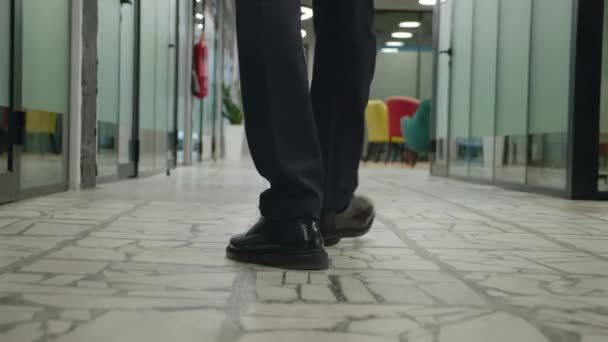 Resmi takım elbiseli iş adamının bacakları ofis koridorunda yürüyor. Açık uzay ofis koridorunda yürüyen tanınmayan bir erkek girişimcinin arkası.. — Stok video