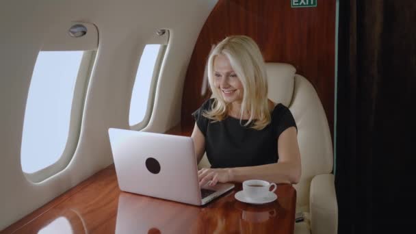 Mulher madura bonita milionário em avião trabalhando no laptop e beber café. Empresária em jato particular ou primeira classe de negócios com computador. Viagem de luxo. — Vídeo de Stock