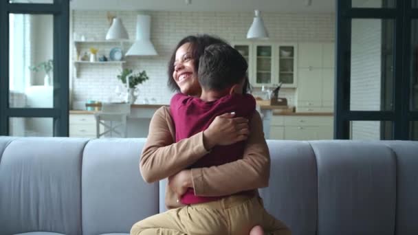 Adorable niño de raza mixta abrazando suavemente a su amorosa madre afroamericana. Mujer disfrutando del tiempo con su lindo hijo. Feliz concepto de relaciones familiares perfectas. Cuidado, ocio en casa, día libre en casa. — Vídeo de stock