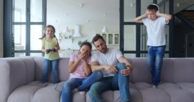 Aktif çocuklar yorgun ve sıkılmış ailelerine yakın koltukta dijital aletlerle zıplamaktan zevk alırlar. Sevimli kız joystickle oynuyor ve yakışıklı oğlan kulaklıkla müzik dinliyor. 4 K video kaydı