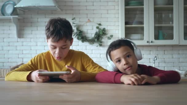 Két imádnivaló afro-amerikai etnikai gyerek digitális elektronikus táblagépet használ, vezeték nélküli fülhallgatóban hallgatják a zenét a hétvégéjükön, egy iskolamentes napon. Családi program. Testvérek együtt — Stock videók