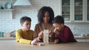 Afrika kökenli Amerikalı anne ve çocuklar düşen kulede oynuyorlar, mutfaktaki masada oturuyorlar. Bekar bir anne ve iki sevimli çocuğun ailesi evde eğitim oyunlarından zevk alıyorlar.