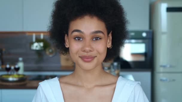 Közelkép a fiatal afro-amerikai nőről, aki a kamerába néz, aztán édesen mosolyog, és fogas mosolyt terjeszt.. — Stock videók