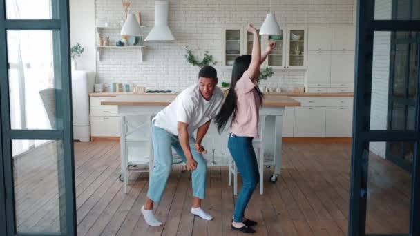 Feliz joven romántico interracial heterosexual pareja de asiáticos esposa y mestizo raza afroamericana marido bailando en la moderna cocina en casa, hermosa gente disfrutando de su fin de semana juntos. — Vídeo de stock