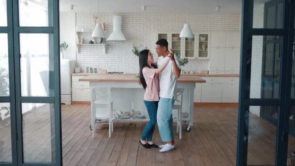 Vackra romantiska interracial heterosexuella par asiatiska kvinna flickvän och afroamerikanska kille pojkvän dansar långsam dans i det moderna köket hemma, njuter av sin lediga dag tillsammans — Stockvideo