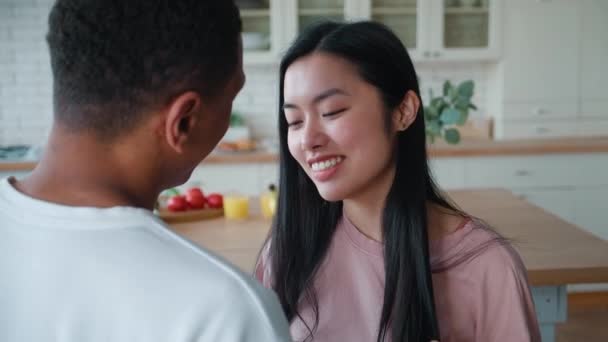 En bedårande ung asiatisk kvinna som ser bra ut på sin afrikanska pojkvän gillar att smeka håret, smekningar och stunder tillsammans. Glad interracial par tillsammans hemma njuter av lediga dagar — Stockvideo