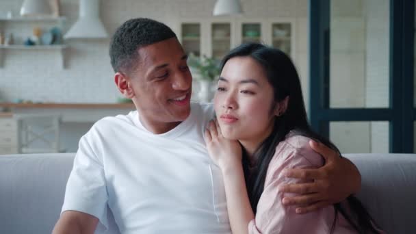 Close-up confident portrait of a happy interracial young couple enjoying time together, African American guy gently embracing his Asian girlfriend leaning on his shoulders, communicating together — Stock Video