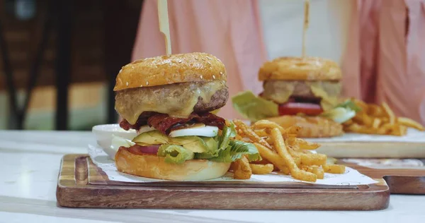 Etli ve sebzeli büyük iştah açıcı burger masada, aşırı yeme konseptinin yanında duruyor. Kilo kontrolü, aşırı kalori sayımı, abur cubur bağımlılığı.