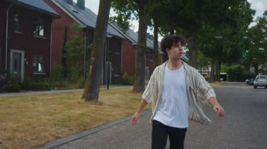 Enerjik genç adam hızla yakına geliyor, hayat dolu genç erkek mahallede aceleyle yürüyor, dinamik ergen erkek enerjik adımlarla yerel caddeleri dolaşıyor.