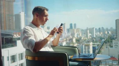 Şok olmuş işadamı modern şehir ofisindeki akıllı telefondan kötü haberler okuyor sonra da panikliyor. Son dakika haberi: Mali belirsizlik piyasa çöküşü zihinsel sağlık baskısı kavramı.