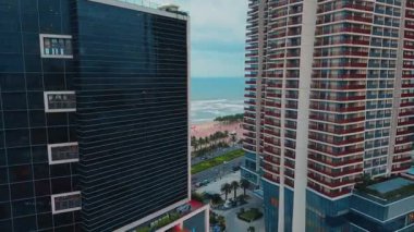 Okyanusa ve sahile bakan kuleleri olan deniz kenarındaki yüksek binalar. Modern kıyı şehri, yoğun şehir turizmini ve tropikal çevreyi gösteriyor. Danang, Vietnam.