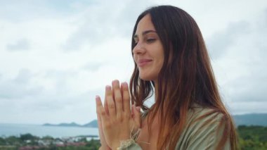 Farkındalık kadını, elleri birarada, dışarıda duruyor ve doğada sakin bir anın tadını çıkarıyor. Farkındalık, iç huzuru dengeler. Minnettarlık, manzara ve duygusal refah.