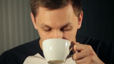 genç adam çay beyaz bir bardaktan içiyor.