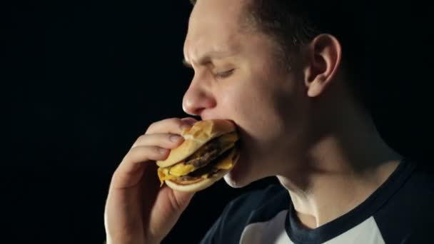 Young man eats a burger — Stock Video