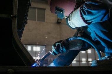 Fabrika kaynakçılar göz kamaştıran bir ışık çalışırken