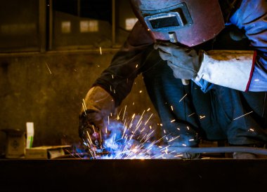 Fabrika kaynakçılar göz kamaştıran bir ışık çalışırken