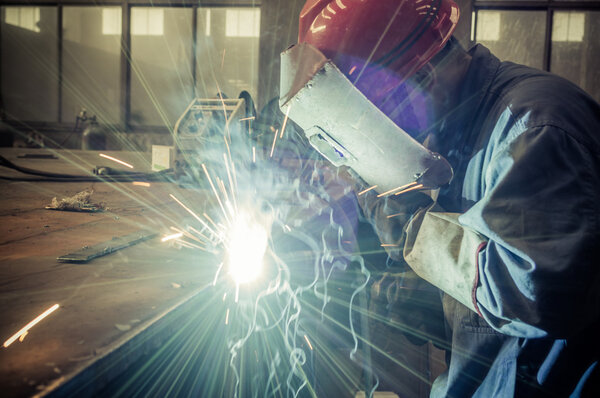 Когда фабричные сварщики работают ослепительный свет
