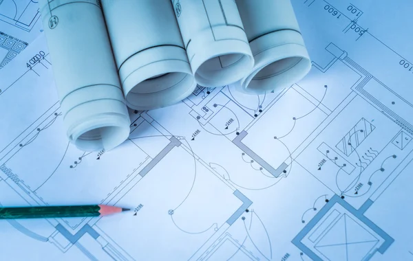 Planos arquitectónicos y rollos de planos y un instrumento de dibujo en la mesa de trabajo —  Fotos de Stock