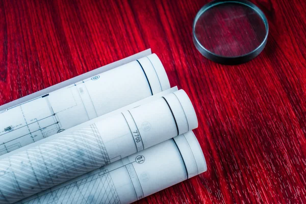 Planos arquitectónicos y rollos de planos y un instrumento de dibujo en la mesa de trabajo — Foto de Stock