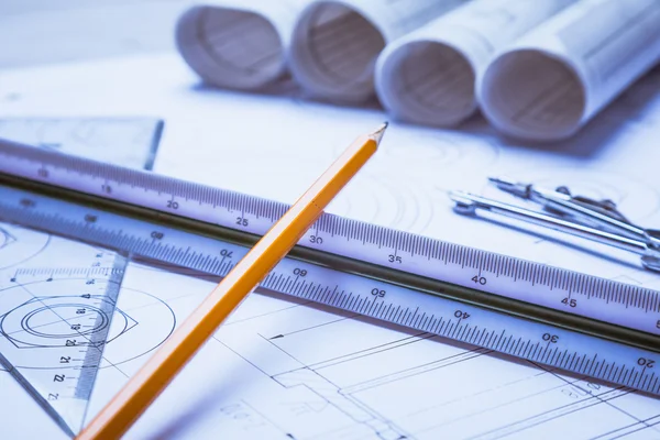 Architectural blueprints and blueprint rolls and a drawing instruments on the worktable — Stock Photo, Image